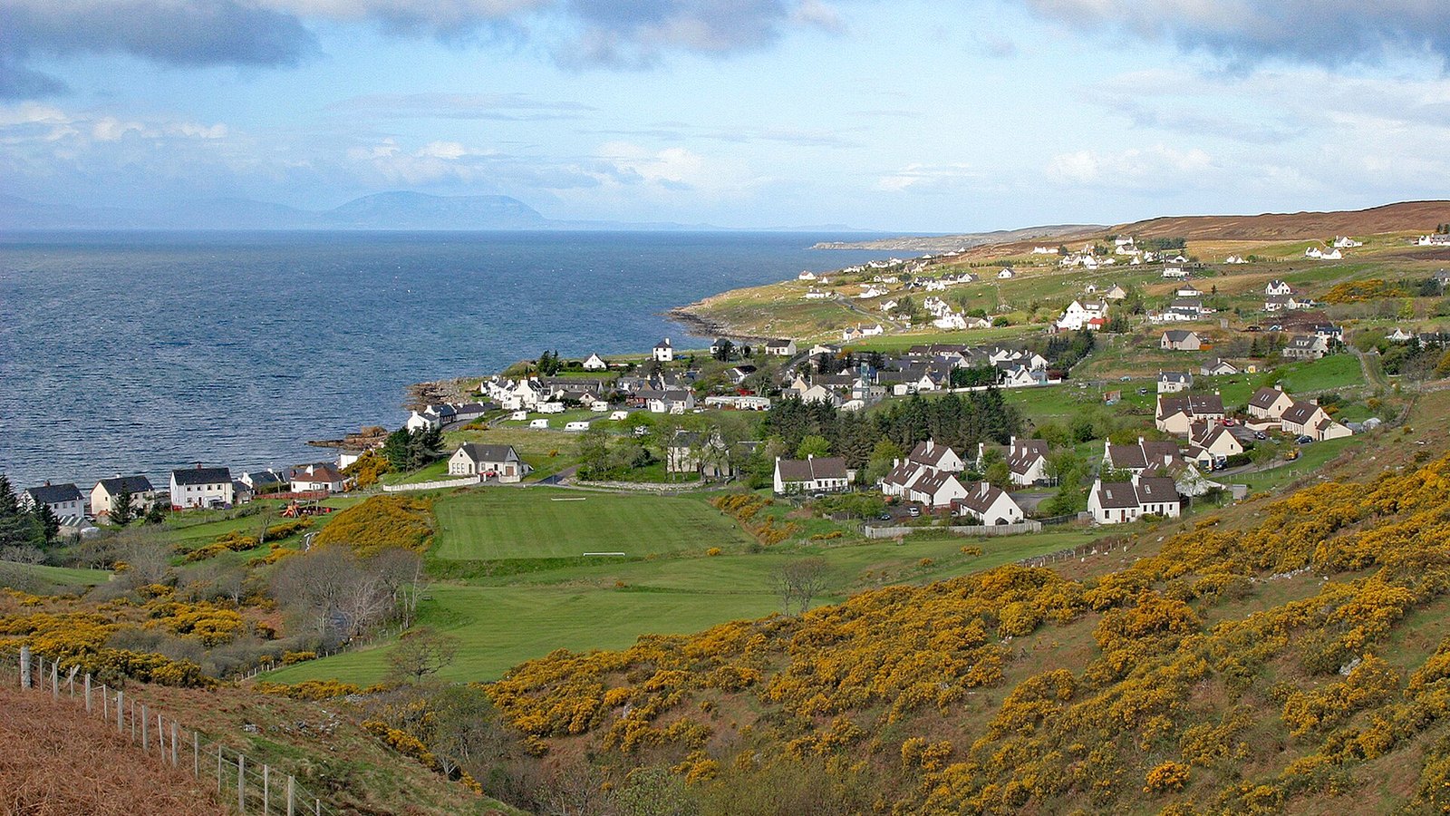 Gairloch's white cottages along the sea loch beneath the Torridon mountains — airport transfers from Gairloch